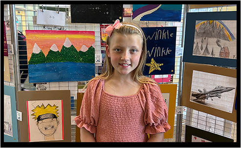 Student standing in front of her art display