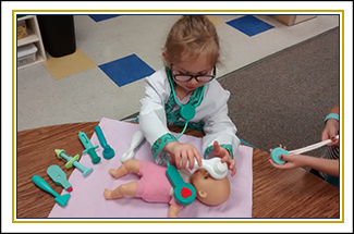 Female student playing as a doctor with a toy baby